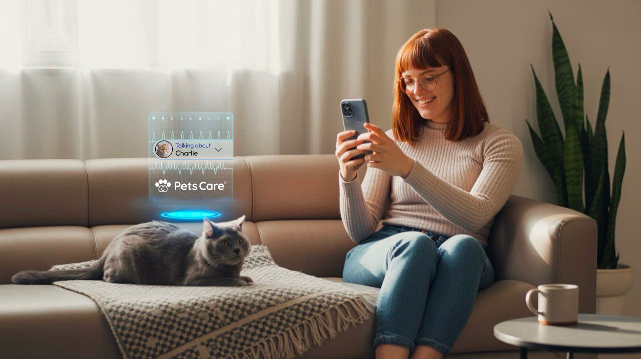 Woman using PetsCare.com app to talk about her cat Charlie, while the cat rests on a couch